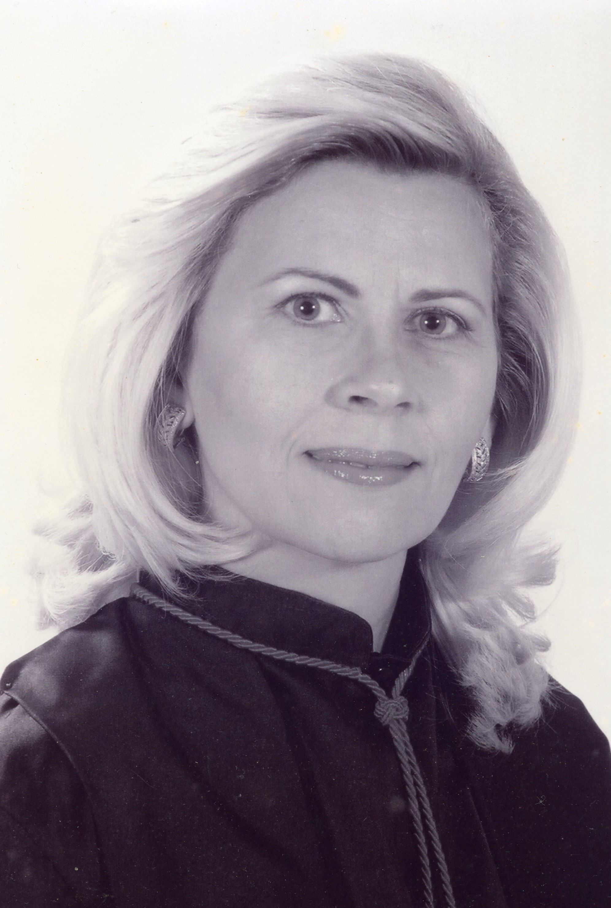 Fotografia em preto e branco, mulher branca, cabelos claros, médio, usando toga.