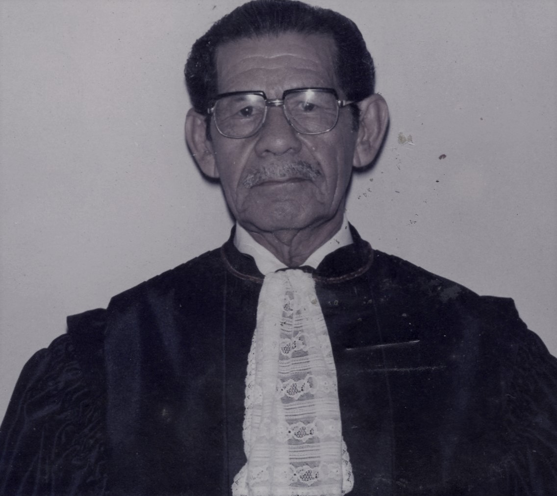 Homem pardo, cabelo preto, usando toga