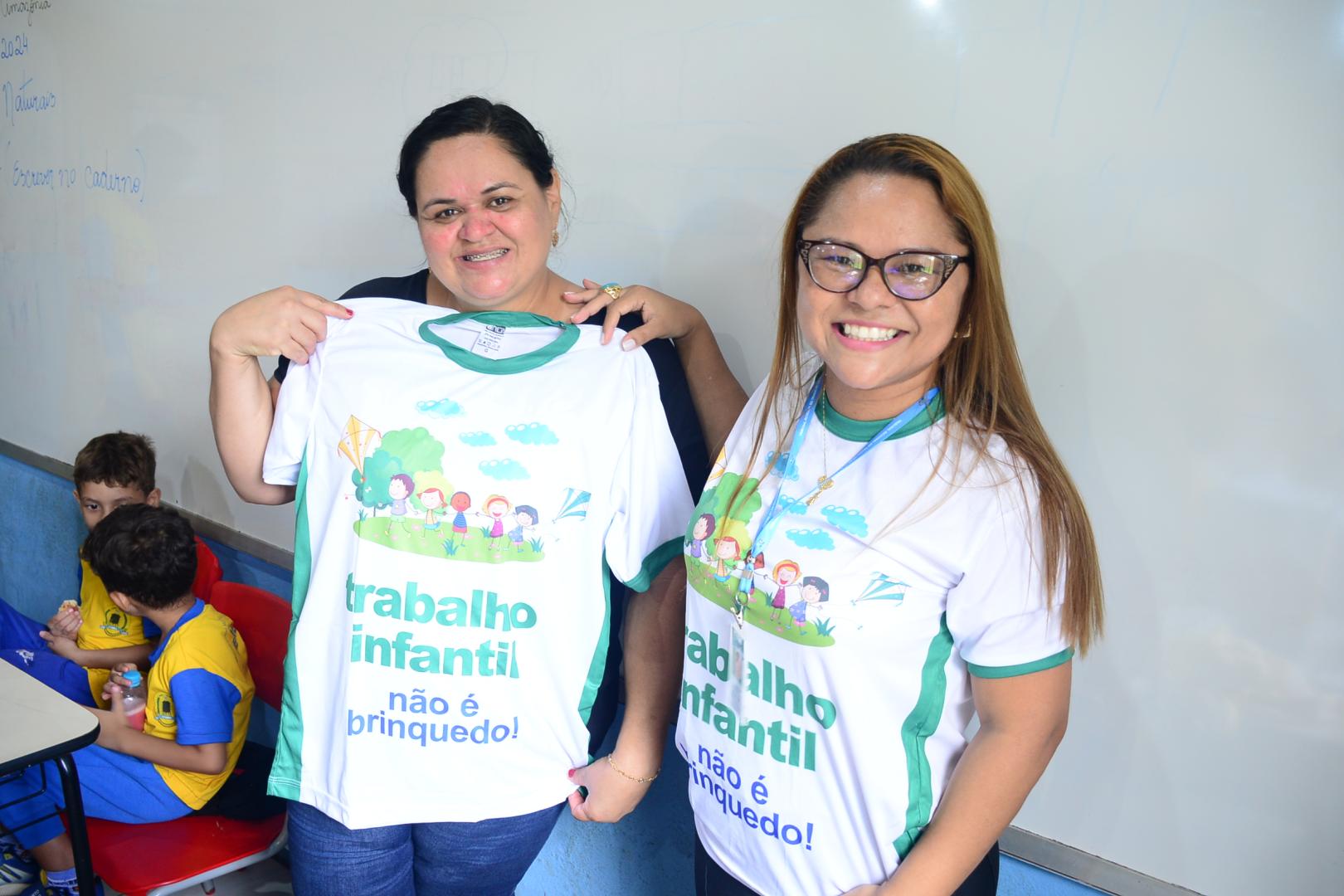 Servidora do TRT-14 fazendo entrega de camisa contra o trabalho infantil à professora