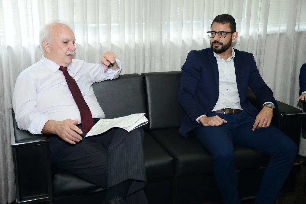 Sentados em um sofá estão o presidente do TRT-14, desembargador Osmar Barneze, e o juiz Auxiliar de Precatórios, Augusto Carigé.